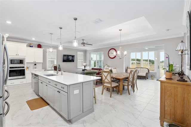 kitchen featuring sink, stainless steel appliances, decorative light fixtures, a center island with sink, and ceiling fan with notable chandelier