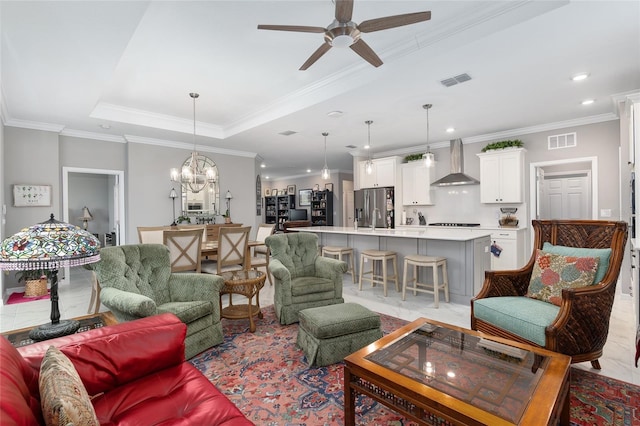 living room featuring sink, a raised ceiling, light tile patterned flooring, ceiling fan with notable chandelier, and ornamental molding