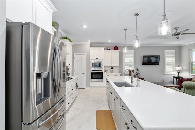 kitchen featuring appliances with stainless steel finishes, sink, decorative light fixtures, a center island with sink, and white cabinets