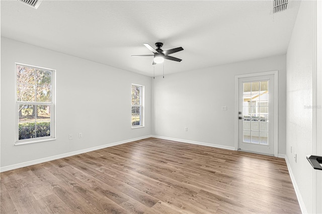 spare room featuring a wealth of natural light, ceiling fan, and hardwood / wood-style flooring
