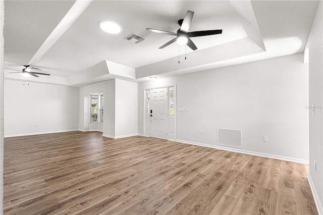 unfurnished living room featuring hardwood / wood-style floors, a textured ceiling, a raised ceiling, and ceiling fan