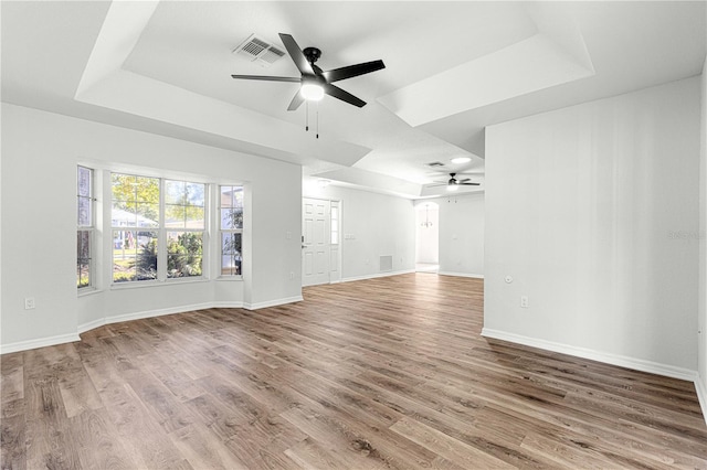 unfurnished living room with hardwood / wood-style floors, ceiling fan, and a raised ceiling