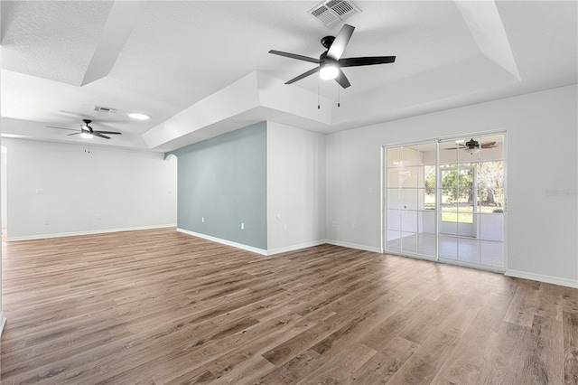 spare room with wood-type flooring, a textured ceiling, and a tray ceiling
