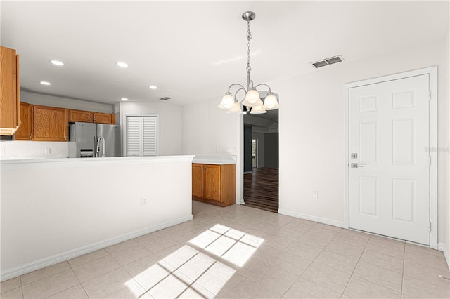 interior space with decorative light fixtures, light tile patterned floors, stainless steel refrigerator, and a chandelier