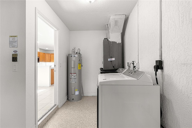 washroom with electric water heater, washer and dryer, and a textured ceiling