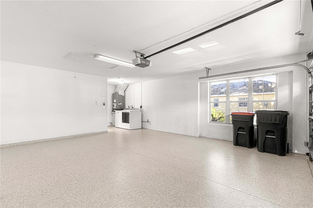 garage featuring electric water heater, a garage door opener, and washing machine and clothes dryer