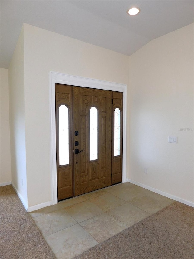 foyer featuring light tile patterned floors and vaulted ceiling