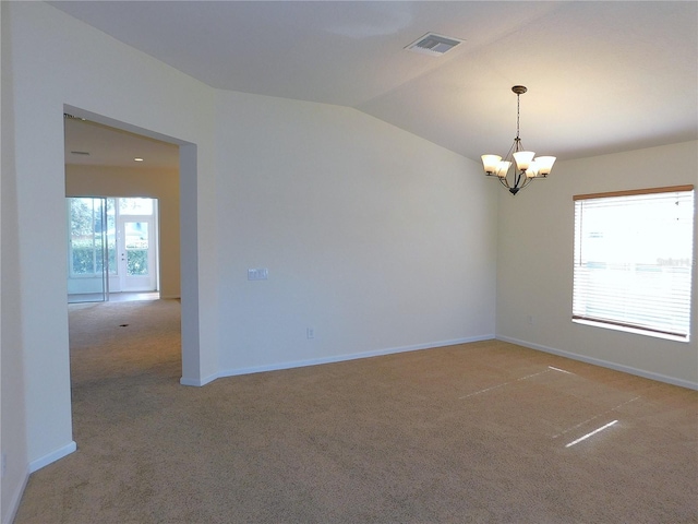 carpeted spare room with vaulted ceiling and an inviting chandelier