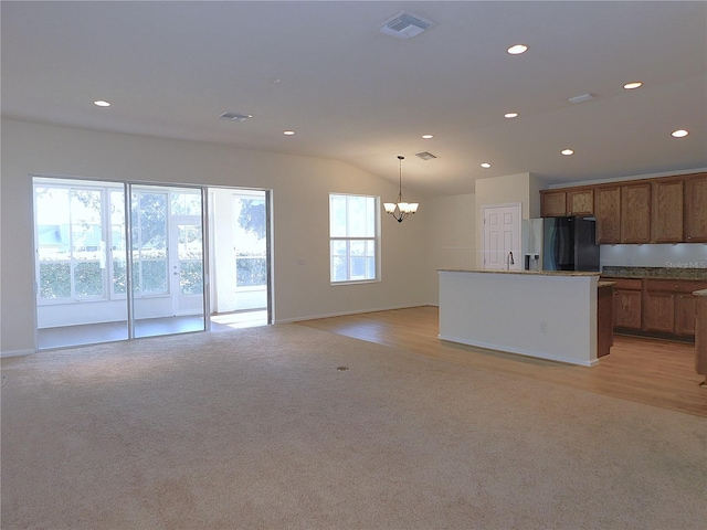 kitchen featuring stainless steel refrigerator with ice dispenser, sink, pendant lighting, a chandelier, and light hardwood / wood-style floors