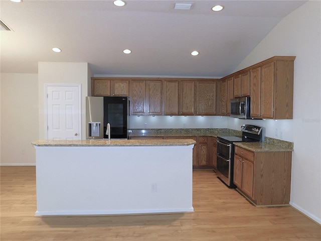 kitchen with a center island with sink, light hardwood / wood-style floors, stainless steel appliances, and vaulted ceiling