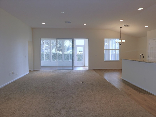 interior space featuring light hardwood / wood-style flooring, a chandelier, vaulted ceiling, and sink