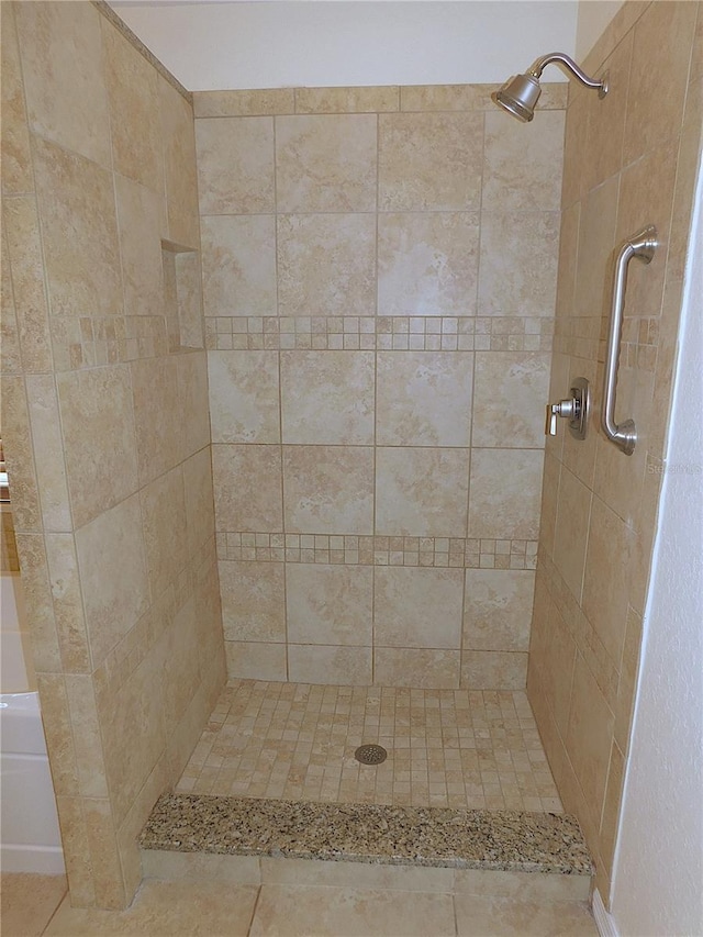 bathroom with tile patterned flooring and a tile shower