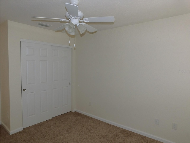 unfurnished bedroom featuring ceiling fan, a closet, and carpet floors