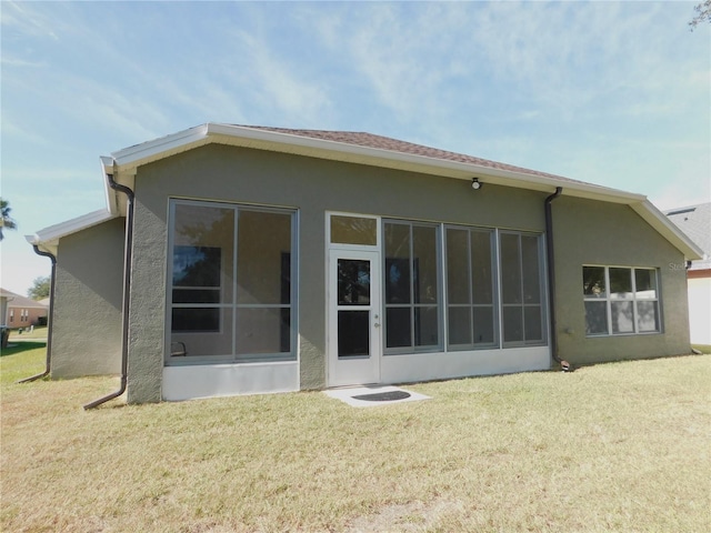 rear view of house featuring a lawn and a sunroom