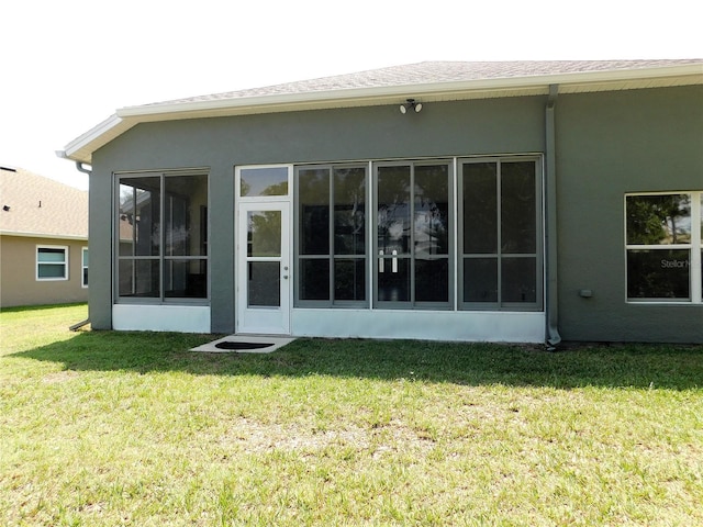 back of property with stucco siding and a lawn