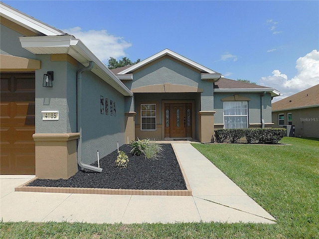 view of front of house with an attached garage, stucco siding, and a front yard