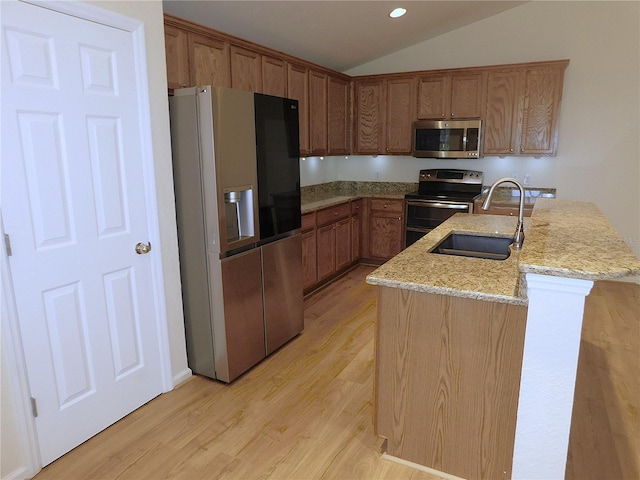 kitchen with a sink, light wood-type flooring, light stone countertops, appliances with stainless steel finishes, and lofted ceiling