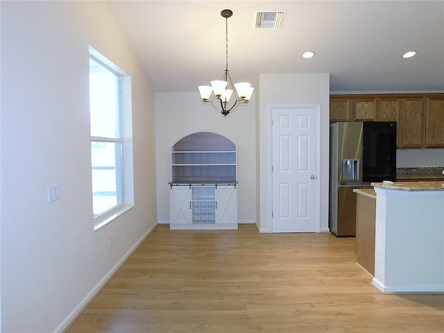 kitchen featuring stainless steel fridge with ice dispenser, light wood-type flooring, visible vents, and a notable chandelier