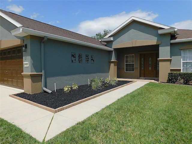 view of front of property featuring stucco siding, a front lawn, and a garage