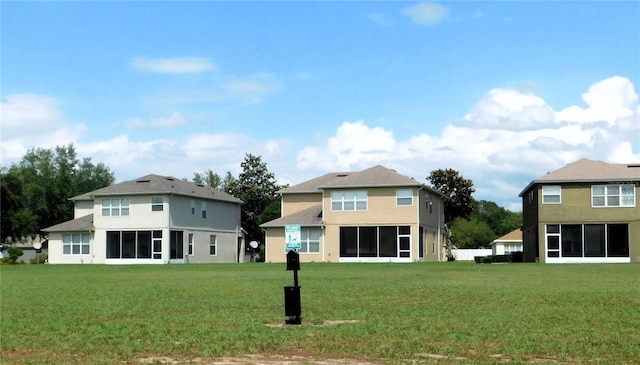 back of property with a sunroom, a yard, and stucco siding