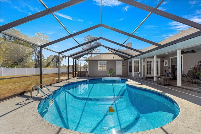 view of swimming pool featuring french doors, ceiling fan, glass enclosure, a patio area, and a lawn