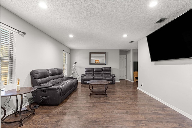 living room with a textured ceiling, a wealth of natural light, and dark hardwood / wood-style floors