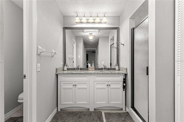 bathroom featuring vanity, a textured ceiling, tile patterned flooring, toilet, and a shower with shower door