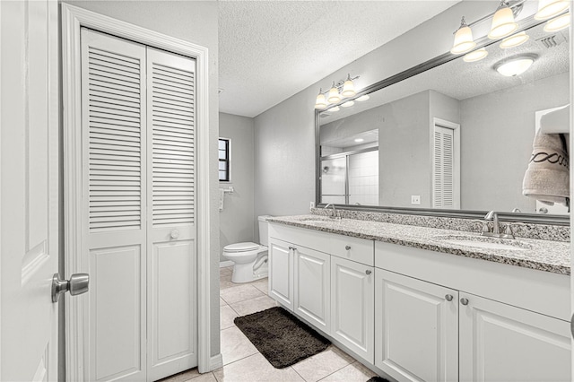 bathroom with tile patterned flooring, vanity, a textured ceiling, and toilet