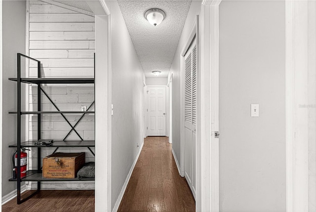 hallway with a textured ceiling and dark hardwood / wood-style floors