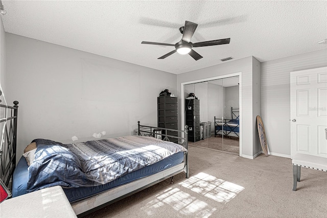 bedroom with ceiling fan, a closet, light carpet, and a textured ceiling