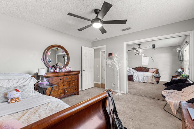 carpeted bedroom with ceiling fan, a textured ceiling, and a closet