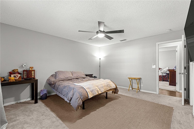 bedroom with a textured ceiling, ceiling fan, and light carpet