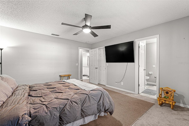 bedroom featuring ceiling fan, light colored carpet, a textured ceiling, and ensuite bath