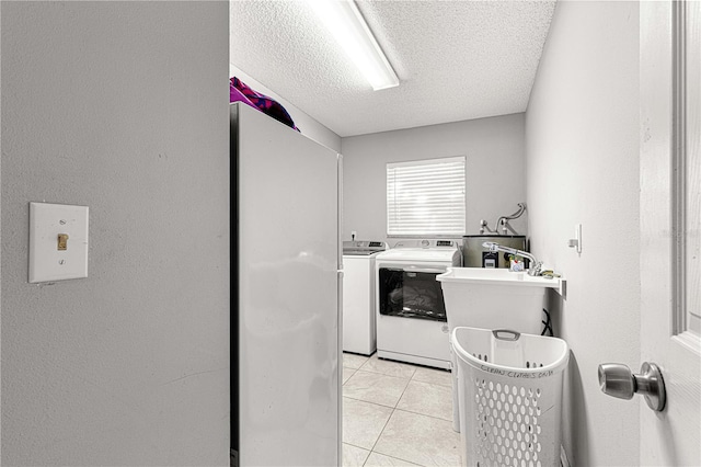 clothes washing area featuring light tile patterned floors, a textured ceiling, electric water heater, and washing machine and clothes dryer