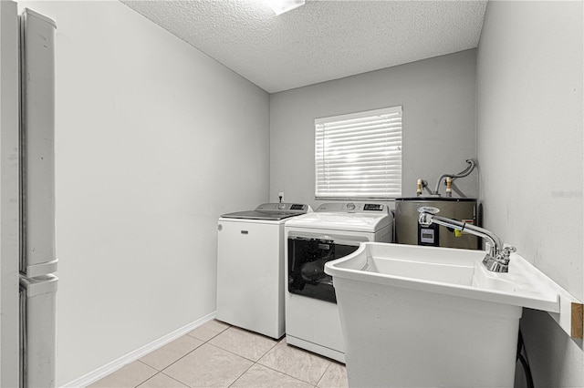 laundry room featuring a textured ceiling, sink, water heater, light tile patterned floors, and washing machine and clothes dryer