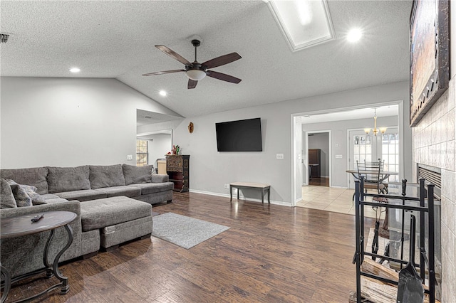 living room featuring wood-type flooring, lofted ceiling, a textured ceiling, and a tile fireplace