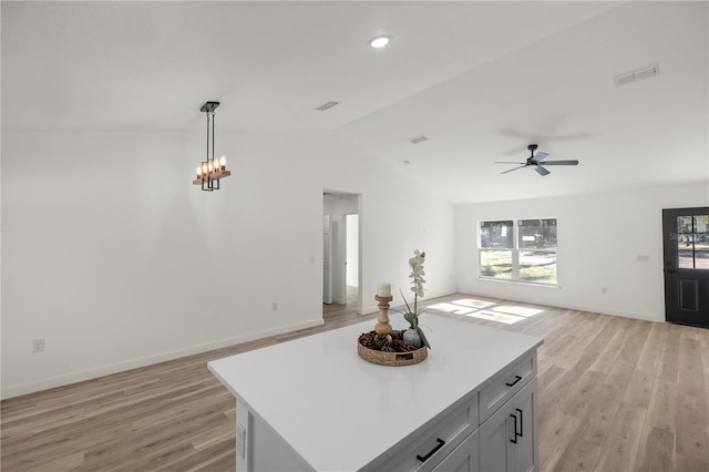 kitchen featuring ceiling fan, hanging light fixtures, light hardwood / wood-style flooring, vaulted ceiling, and a kitchen island