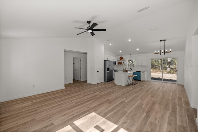 unfurnished living room with ceiling fan with notable chandelier, light hardwood / wood-style floors, and vaulted ceiling