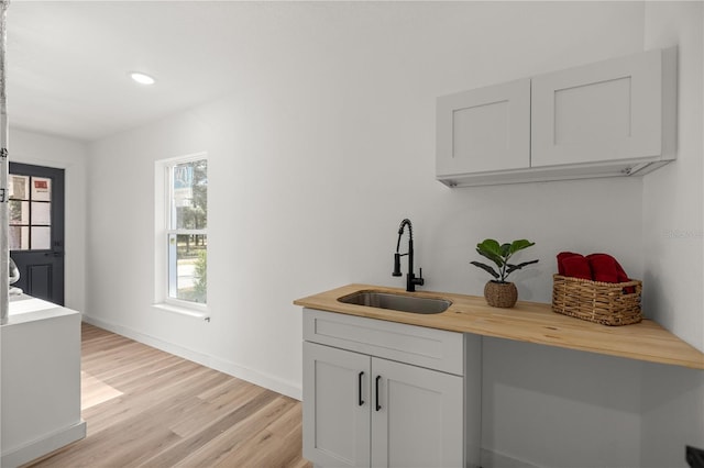 bar with wooden counters, light hardwood / wood-style flooring, a healthy amount of sunlight, and sink