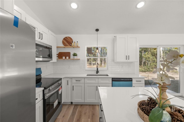 kitchen featuring white cabinets, stainless steel appliances, a healthy amount of sunlight, and sink