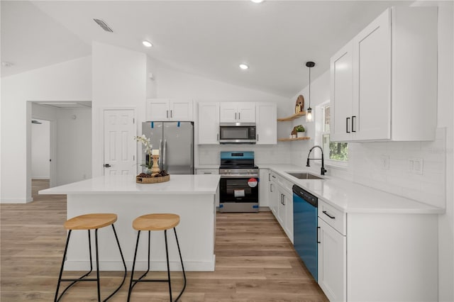 kitchen with white cabinets, stainless steel appliances, lofted ceiling, and sink