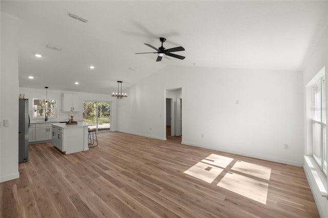 unfurnished living room featuring light hardwood / wood-style flooring, ceiling fan with notable chandelier, lofted ceiling, and sink