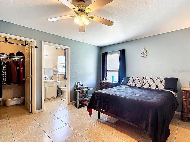 bedroom with ensuite bathroom, ceiling fan, a spacious closet, a textured ceiling, and a closet