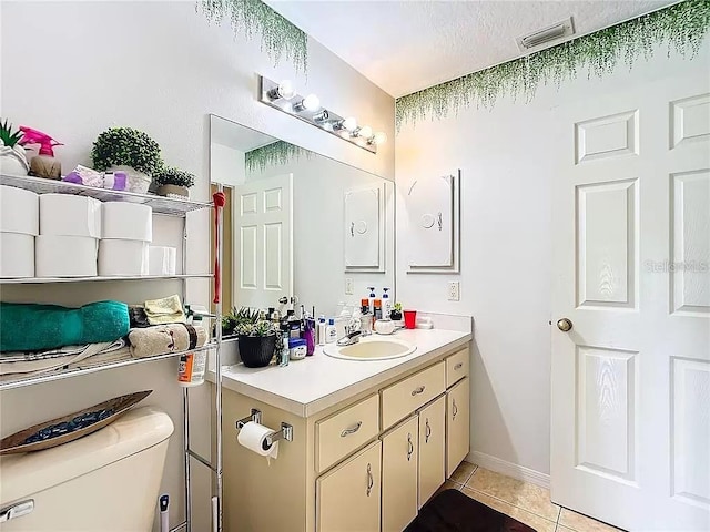 bathroom featuring toilet, a textured ceiling, vanity, and tile patterned floors