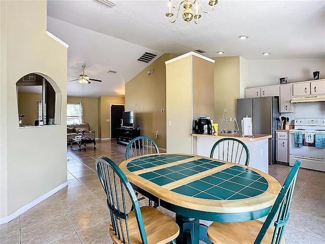 dining area with a textured ceiling, ceiling fan with notable chandelier, lofted ceiling, and light tile patterned flooring