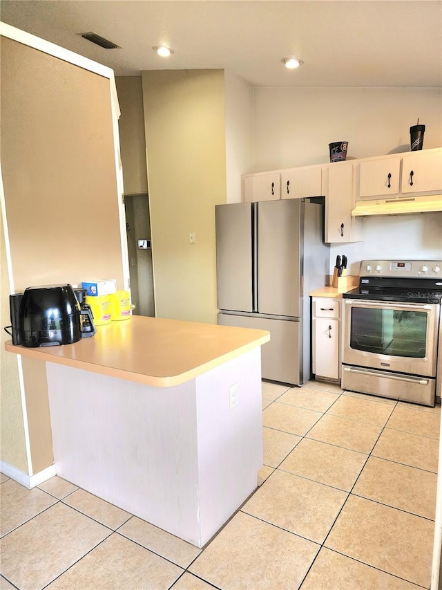 kitchen with lofted ceiling, light tile patterned floors, appliances with stainless steel finishes, cream cabinetry, and kitchen peninsula