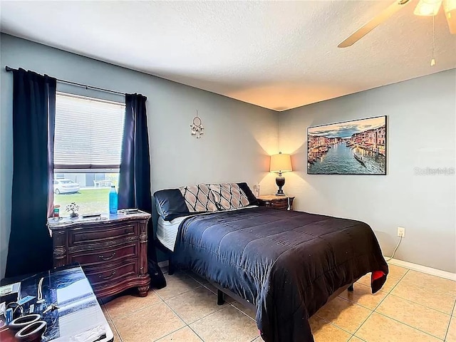 bedroom featuring ceiling fan, light tile patterned flooring, and a textured ceiling