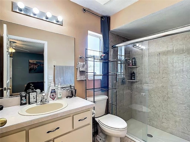 bathroom with ceiling fan, vanity, an enclosed shower, and toilet