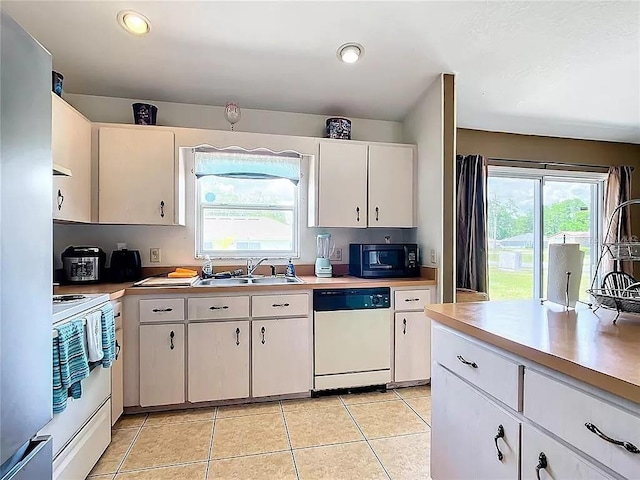 kitchen featuring white cabinets, light tile patterned flooring, white appliances, and sink