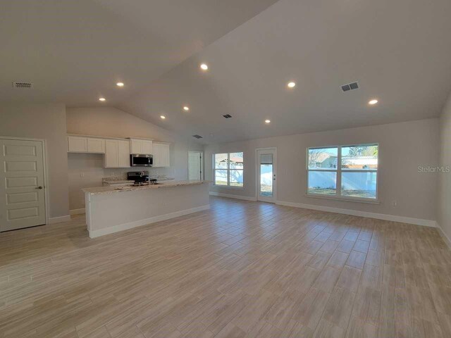 unfurnished living room with high vaulted ceiling and light wood-type flooring